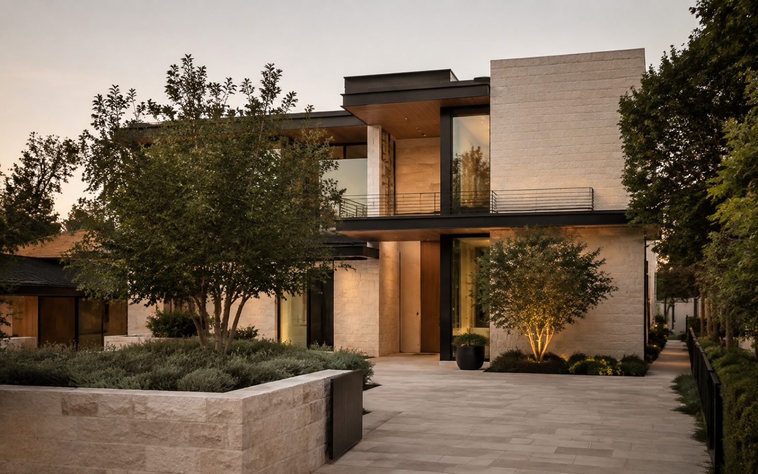 A limestone-clad modern estate photographed at dusk with warm architectural lighting.
